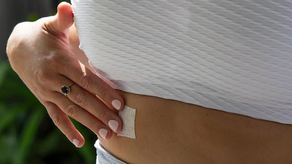 Woman applying a Slim By Nature wellness patch to her stomach