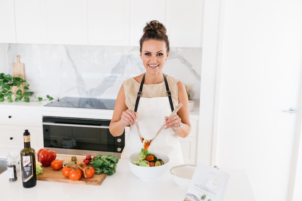 Zhanna Gee, founder of Slim By Nature, preparing a fresh salad in her kitchen